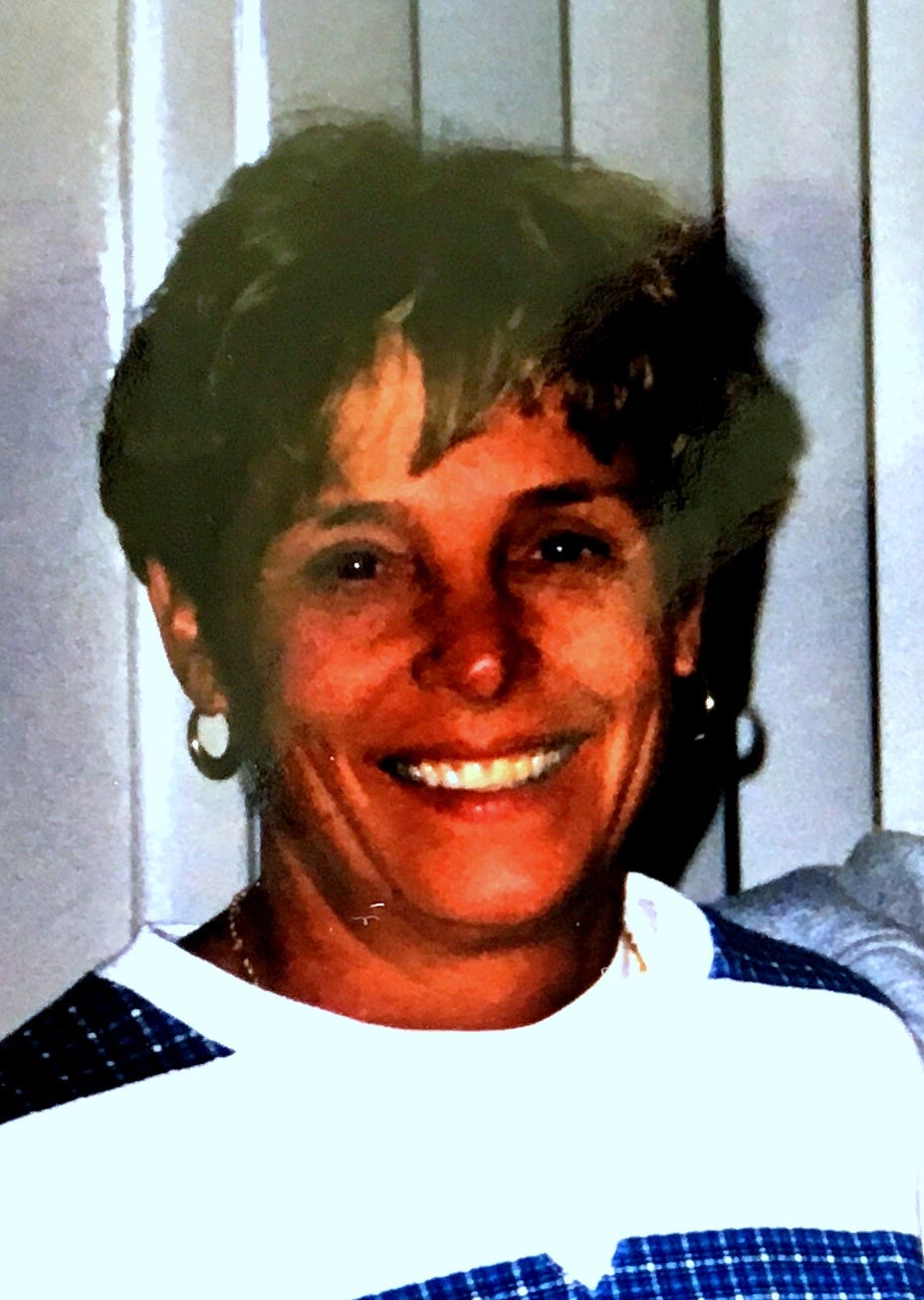 A middle-aged woman with short-cropped hair and gold loop earings smiling
