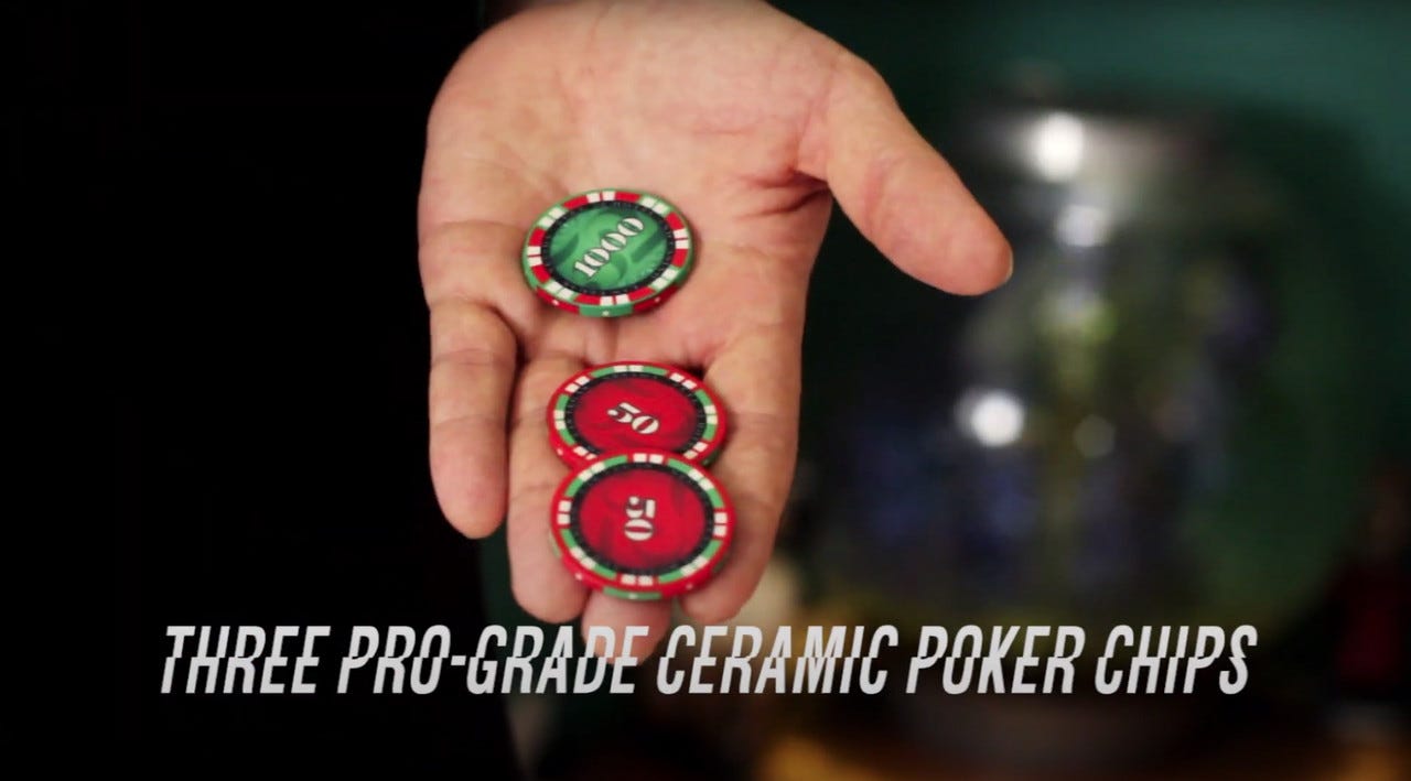 A hand holding three ceramic poker chips, one green and two red.