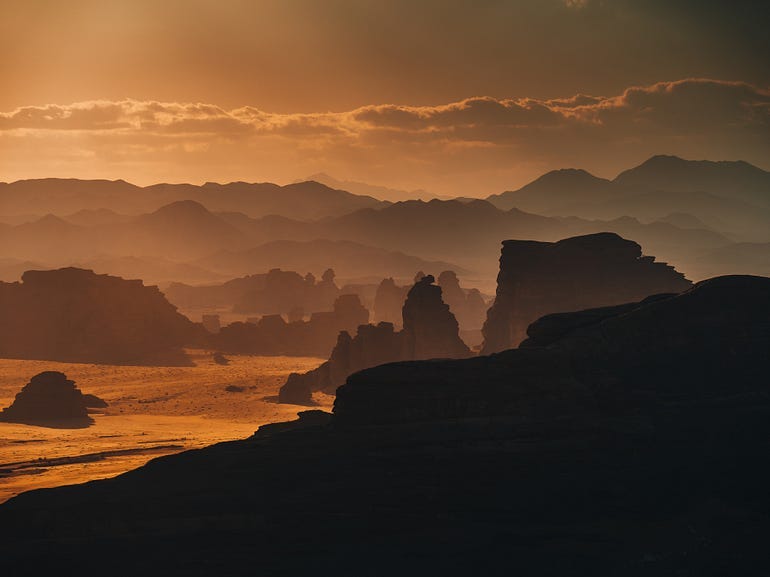 A gorgeous sunset by the rocks and hills of the shore.