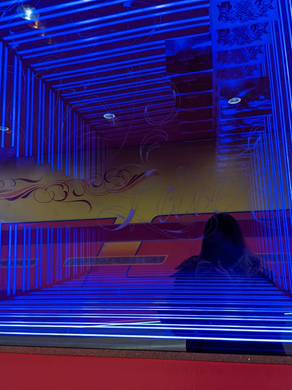 blue striped lights reflecting shadow of a woman and brightly painted wall behind