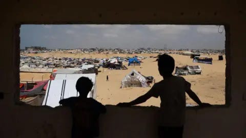 Getty Images Palestinian children stand in a camp for displaced people in Rafah in the southern Gaza Strip by the border with Egypt. 