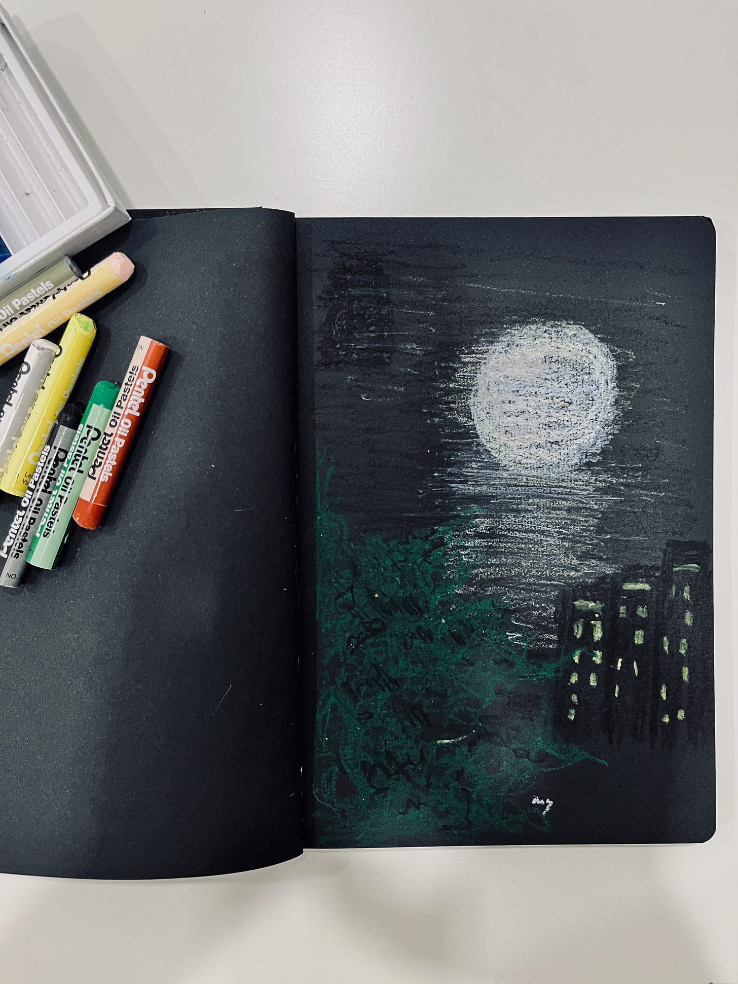 image: a black colour paper notebook with oil pastel sketch of a full moon scene