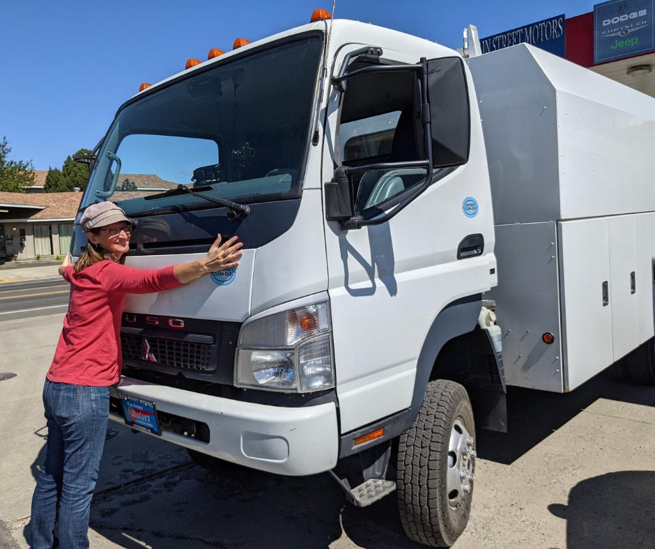 woman smiling and hugging large white commercial truck