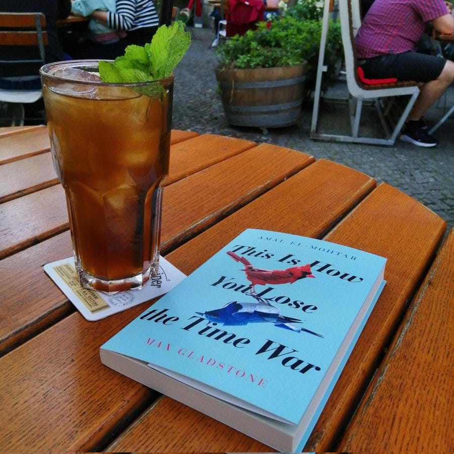 Ein Glas Eistee und das Buch "This is how you lose the time war" auf einem Cafétisch