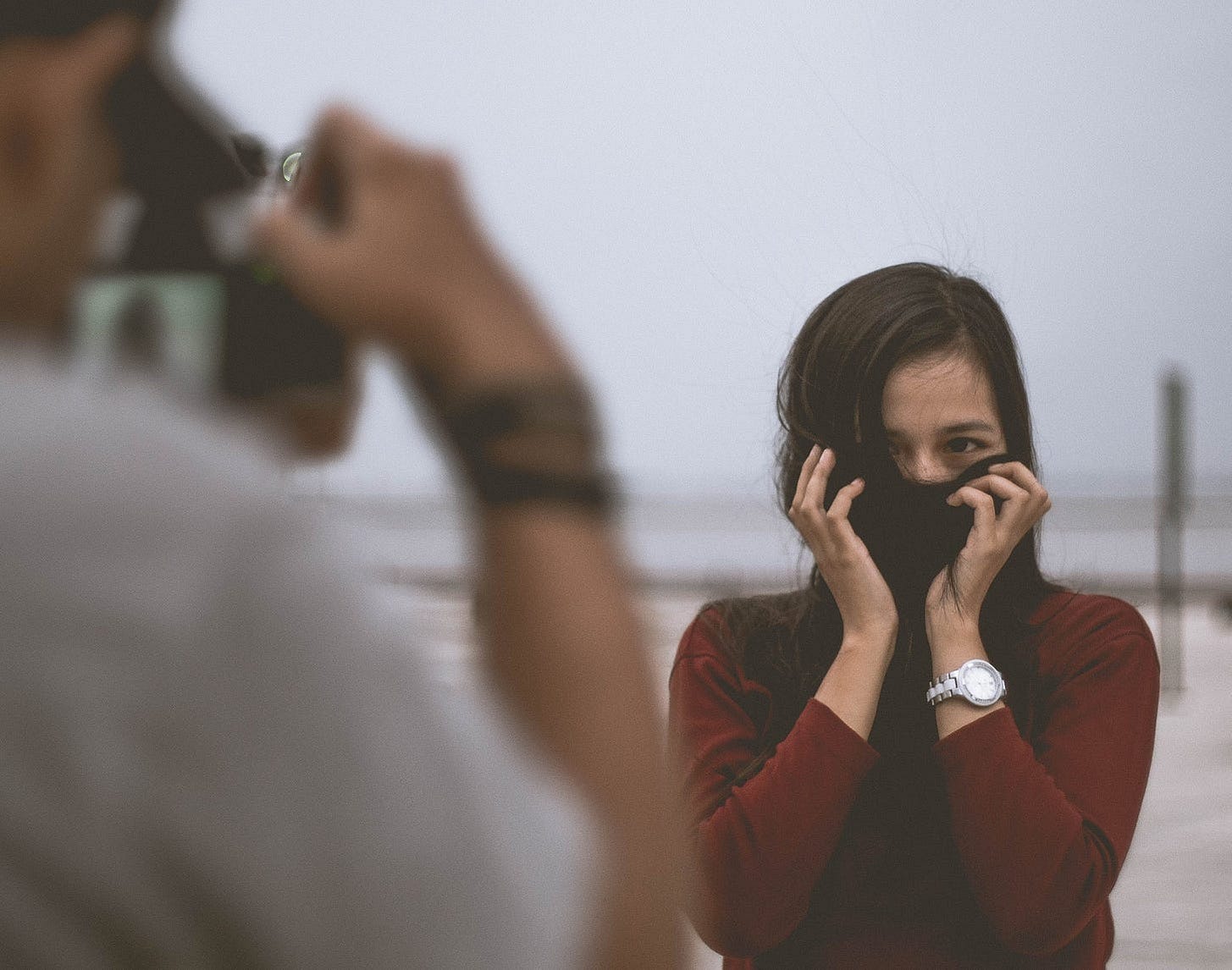 woman hiding her face while a person takes a photograph of her