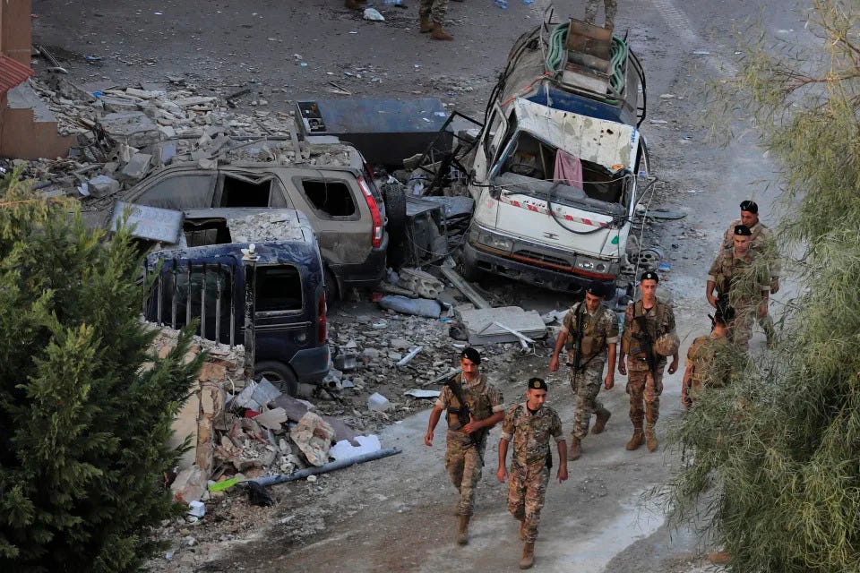 Soldados del ejército libanés caminan junto a coches destruidos en el lugar donde un ataque aéreo israelí alcanzó un edificio, en el pueblo de Barja, al sur de Beirut, Líbano, el sábado 12 de octubre de 2024. (Foto AP/Mohammed Zaatari)