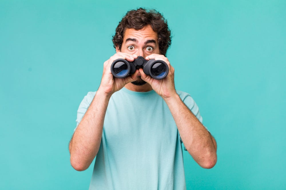 Man looking surprised over a set of binoculars