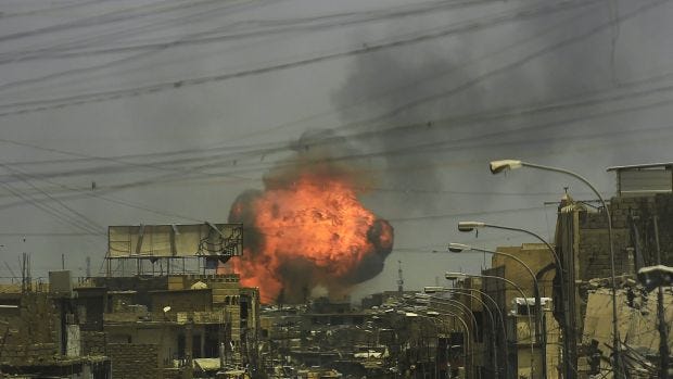 A fireball explodes in the air above the shattered streets of West Mosul on July 3.