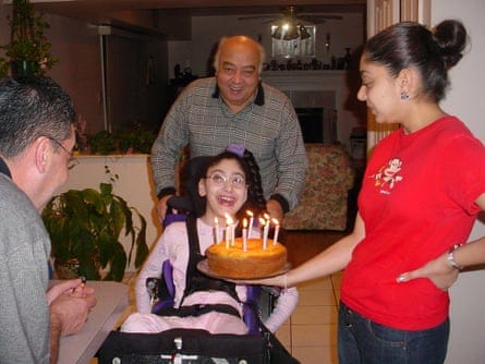 a girl holding a cake as people smile around her 