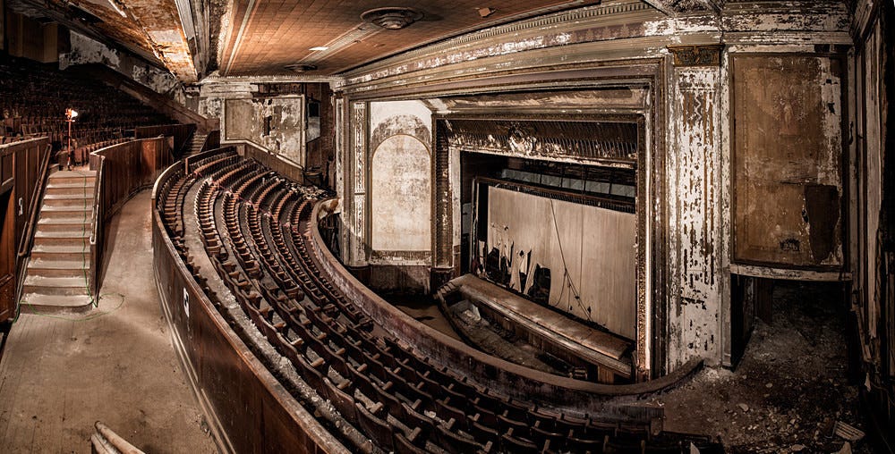 The interior of an abandoned and decaying stage theater from the nosebleed seats
