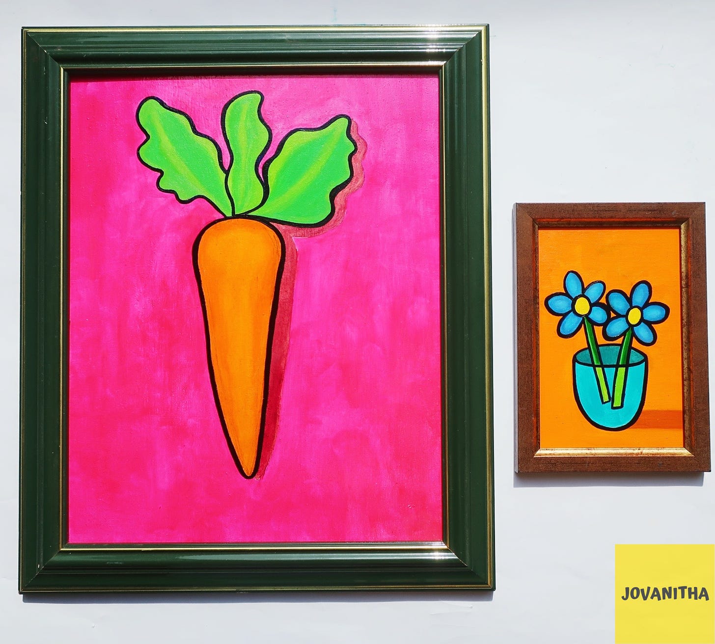 An oil painting of an orange carrot on a pink background and blue forget-me-not flowers in thrifted frames