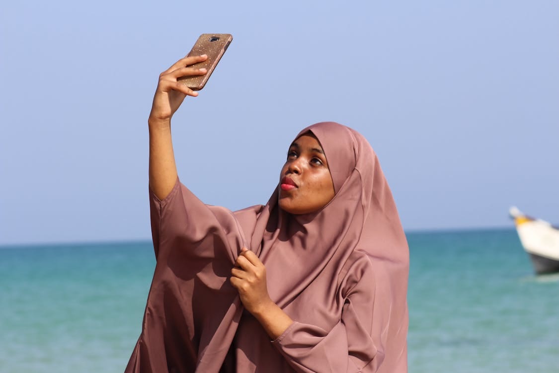 Free Woman in hijab taking a selfie by the sea in Qandala, Somalia. Stock Photo