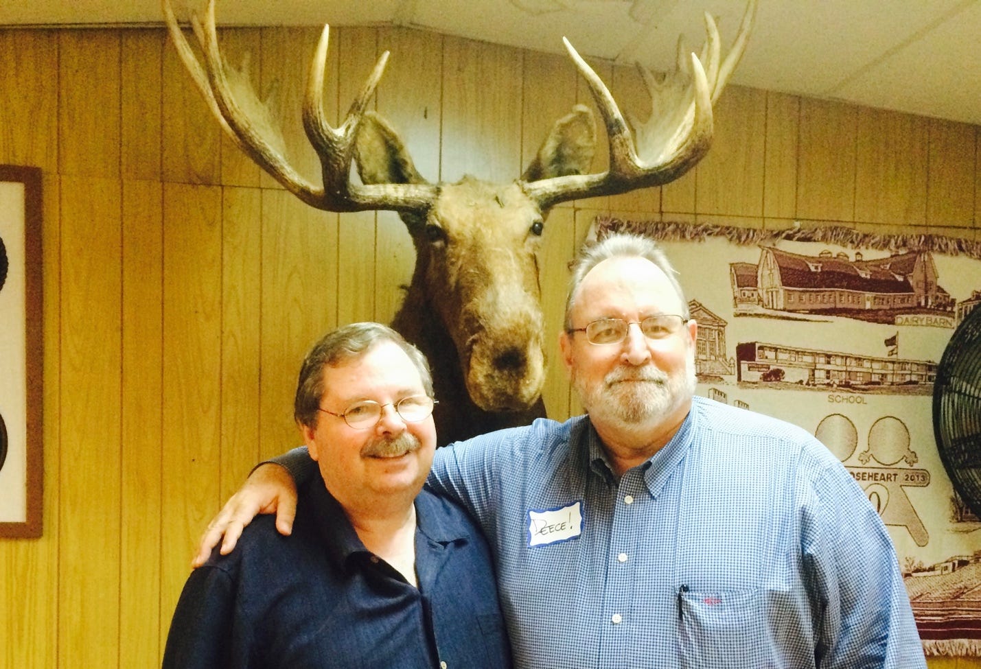 Men standing in front of a moose head

Description automatically generated