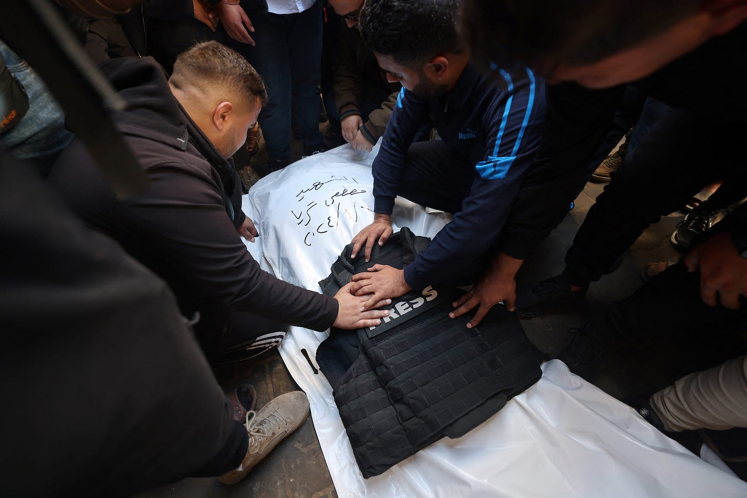  Fellow journalists mourn over the body of Mustafa Thuria, a video stringer for AFP news agency, who was killed in a reported Israeli air strike during his funeral in Rafah in the Gaza Strip on January 7, 2024.