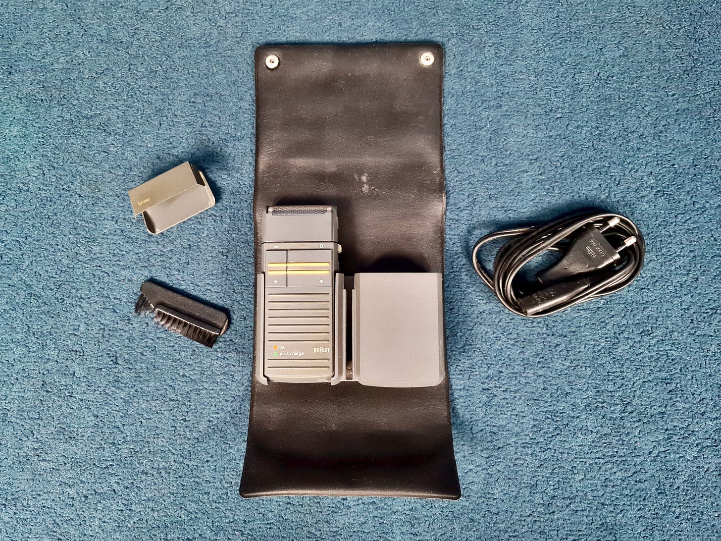 A 1990 Braun Linear electric razor in its soft case, with the end cover, brush, and cable to the side