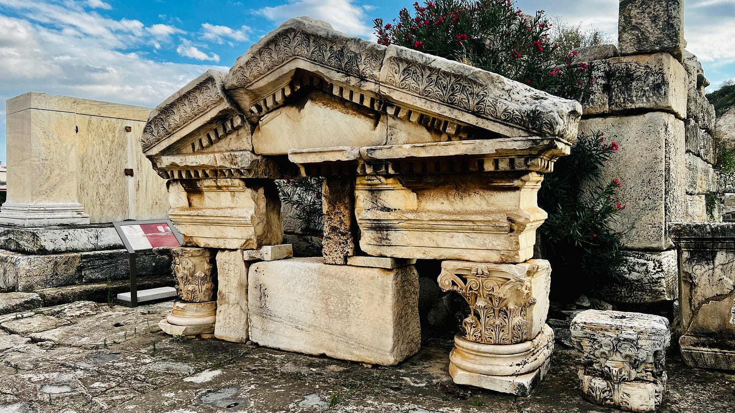 A picture of some components of a small ancient Greek temple on display in an open-air museum.