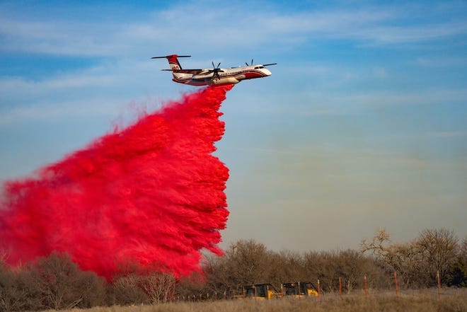 Members of the Texas A&M Forest Service watch as a plane drops fire retardant on a portion of the Smokehouse Creek Fire on Saturday, Mar 02, 2024, in Hemphill County, Texas, after high winds caused a flare-up to reignite the record-breaking fire.