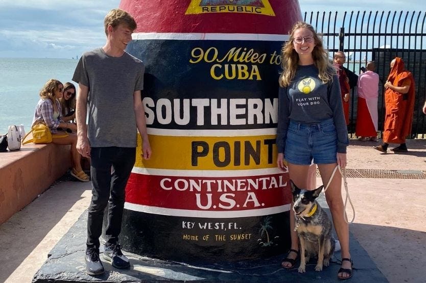 Scout the Australian cattle dog posing for a photo with her owners on Key West at the Southernmost Point of the continental united states