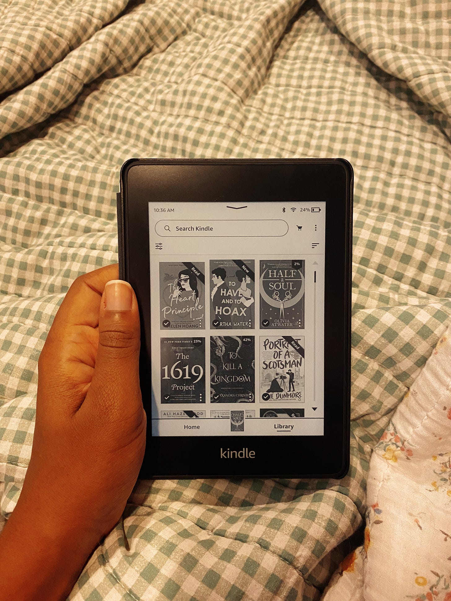 Image of hand holding Kindle over bed