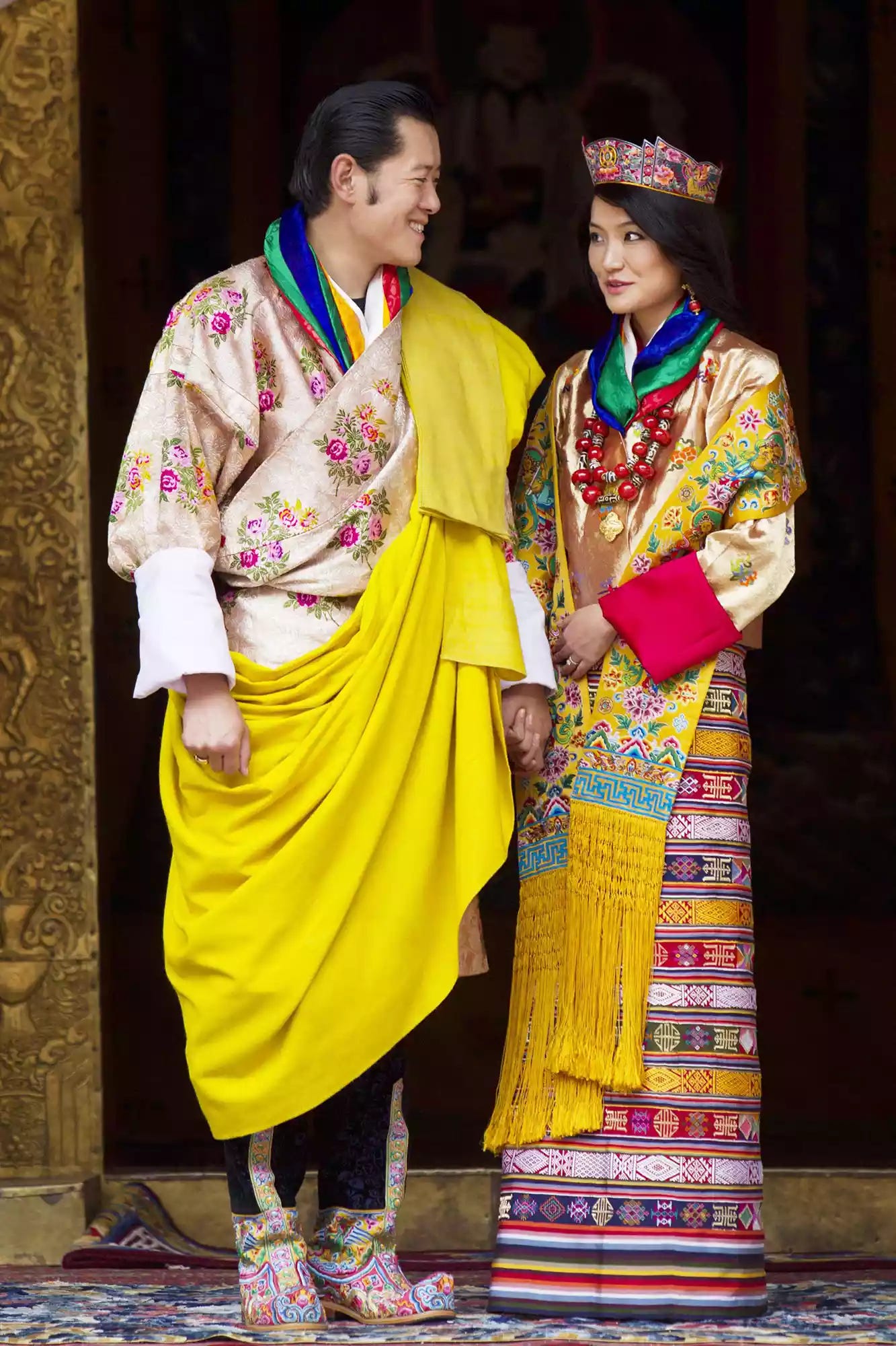 His majesty King Jigme Khesar Namgyel Wangchuck, 31, holds his Raven crown as he and the Queen Jetsun Pema, 21, walk out after their marriage ceremony is completed on October 13, 2011 in Punakha, Bhutan.