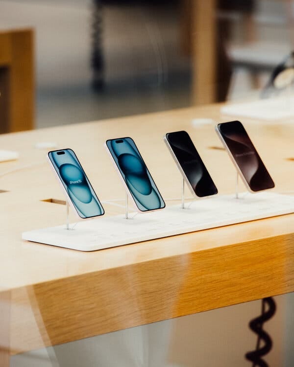 A display of iPhones sits on an oak table.