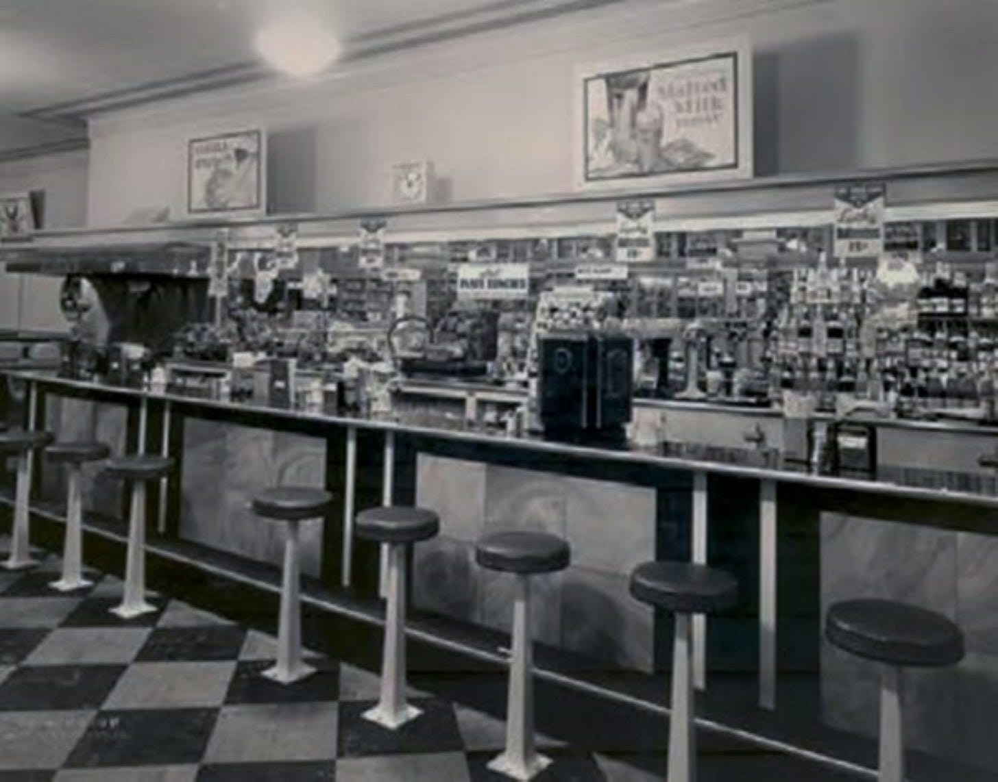Soda fountain from 1950s, stools against a counter with checkerboard tile floor