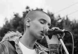 Sinéad O'Connor sings into a microphone.