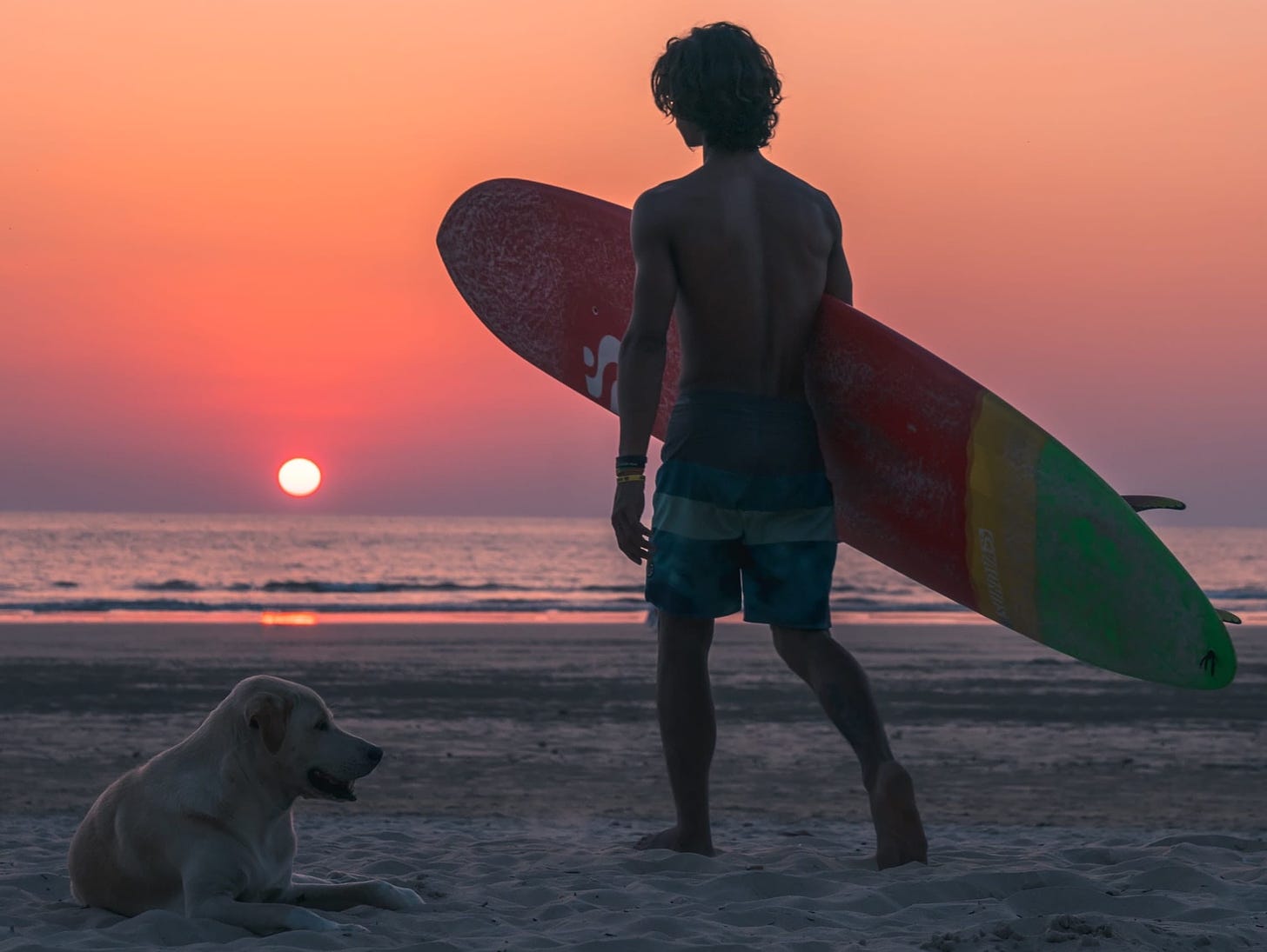 Man with surfboard on the beach at sunset