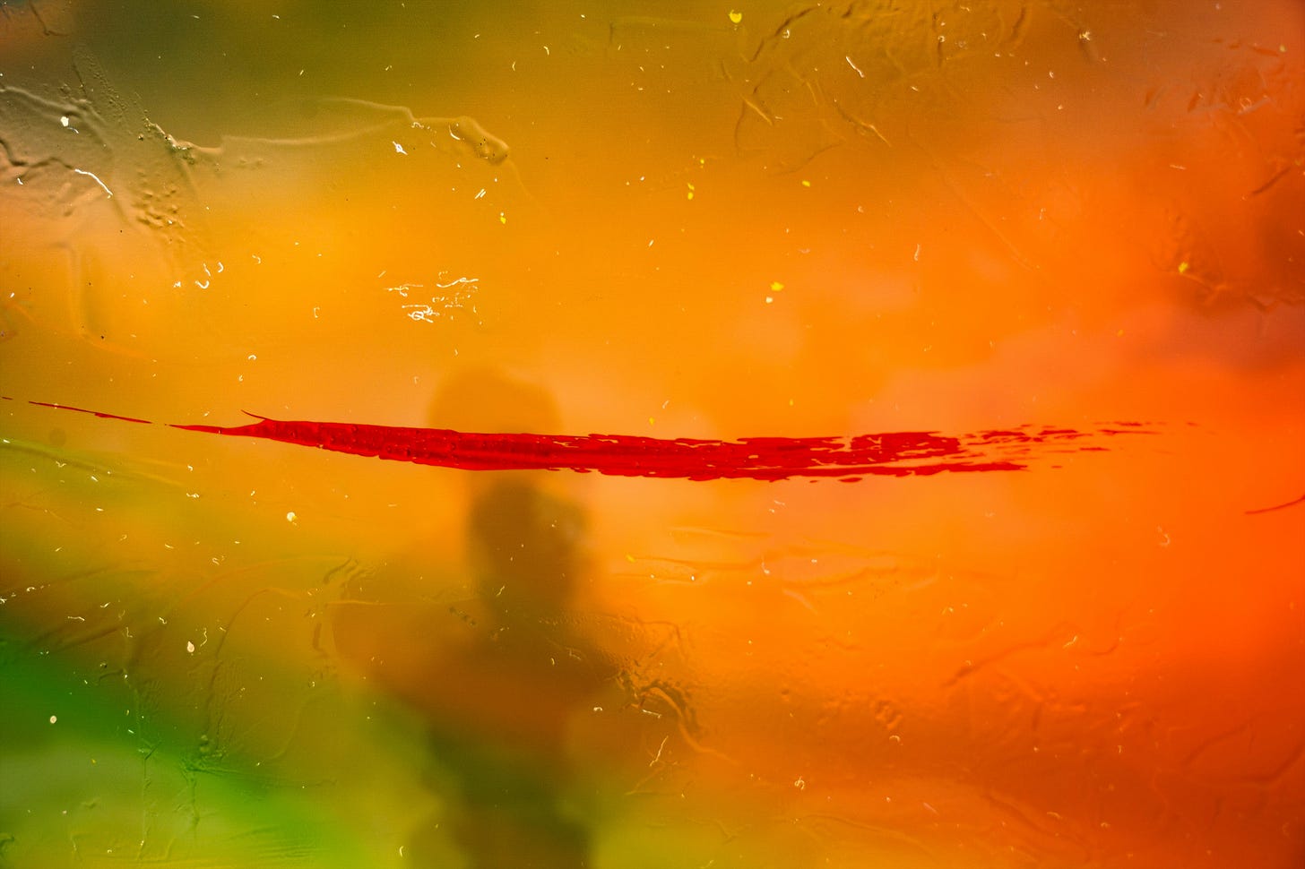 Colorful paint splatters in red and orange on a window.