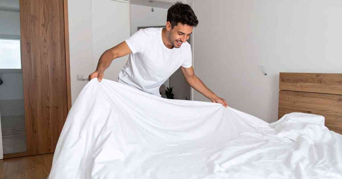 Man making bed in bedroom