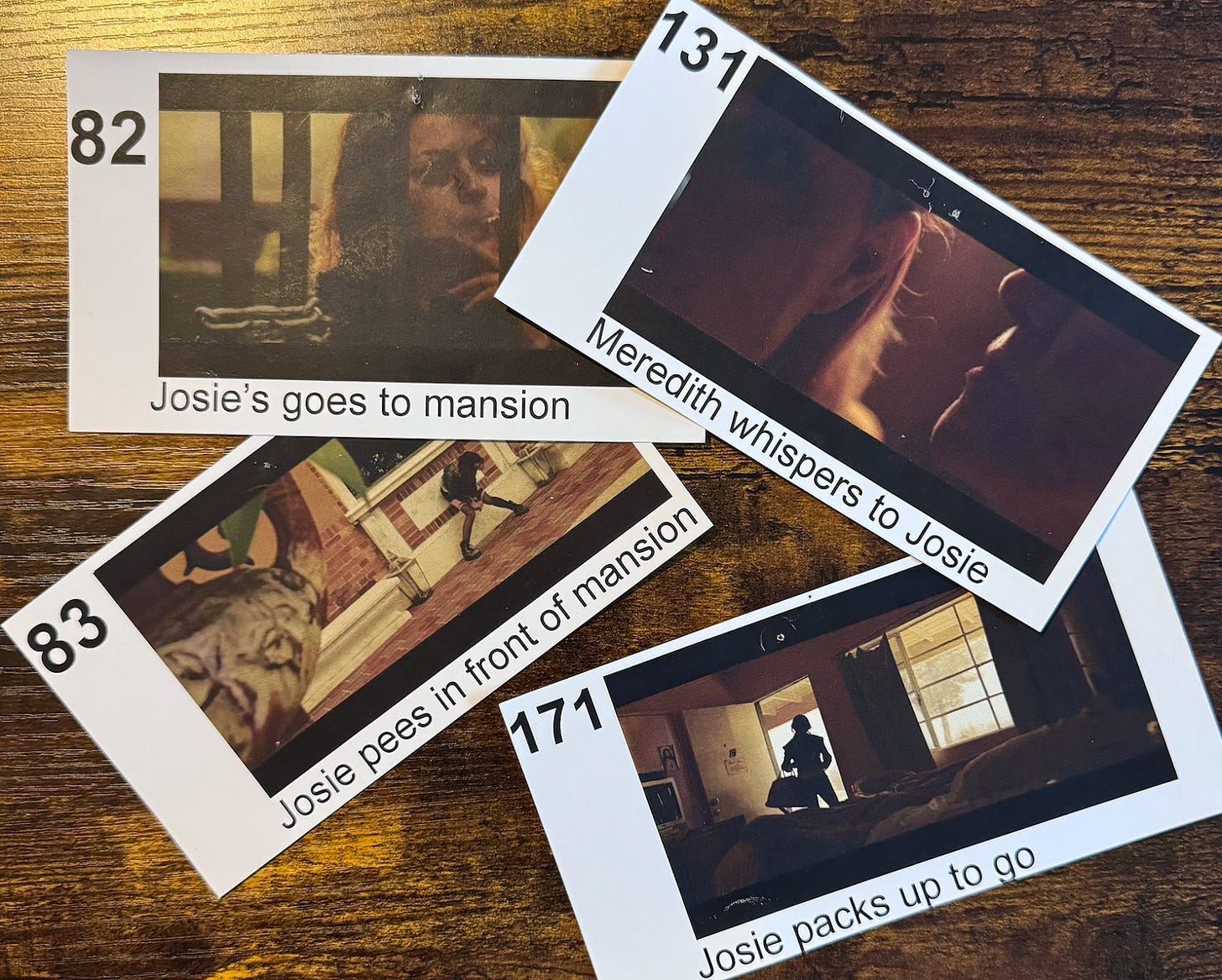 Four numbered cards with stills from the movie "Paint It Black" lay partially overlapping each other. Each card has a description of what is happening in the still. They read, "82: [Josie's] goes to mansion," "131: Meredith whispers to Josie," "83: Josie pees in front of mansion," "171: Josie packs up to go."