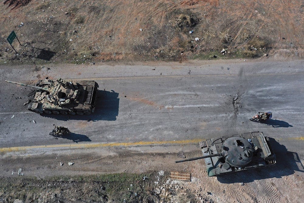 Syrian insurgents ride on motorcycles through abandoned Syrian army vehicles on a road in the outskirts of Hama, Syria, on December 3, 2024.(AP)