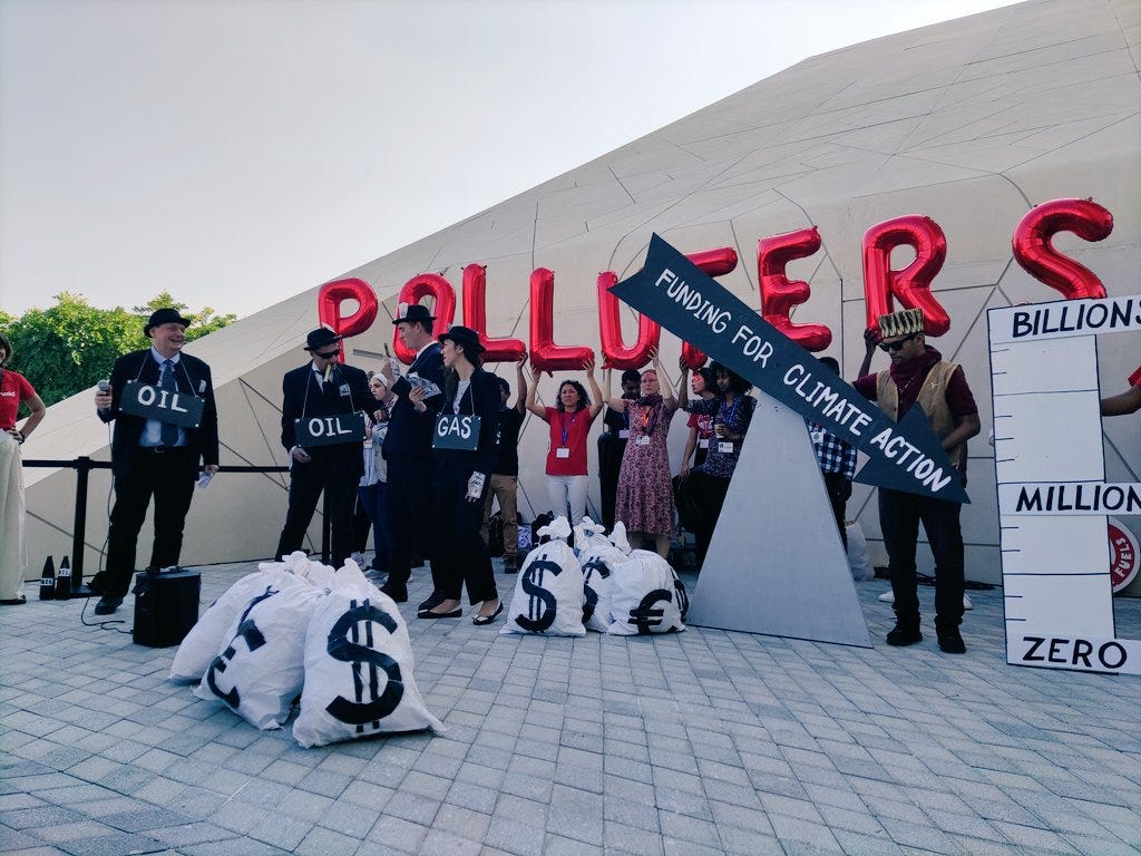 Photo of campaigners protesting calling for funding for climate action paid for by polluters at COP28