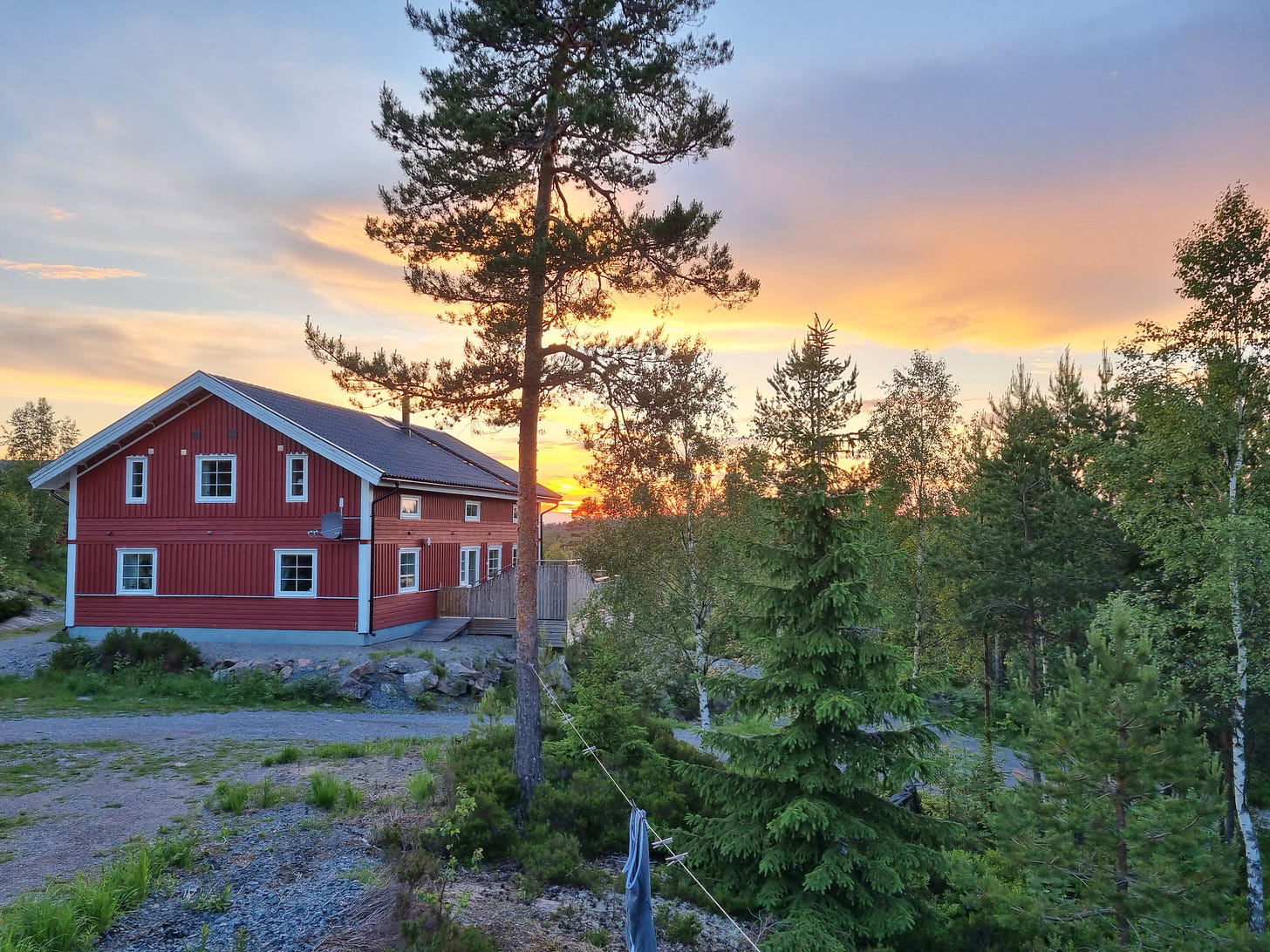 Photo of a sunset with a red cabin in the foreground