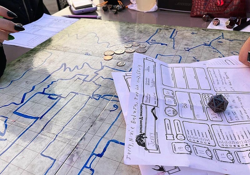 A game of Dungeons & Dragons on a table is shown, with a character sheet taking up the lower left side of the photo.