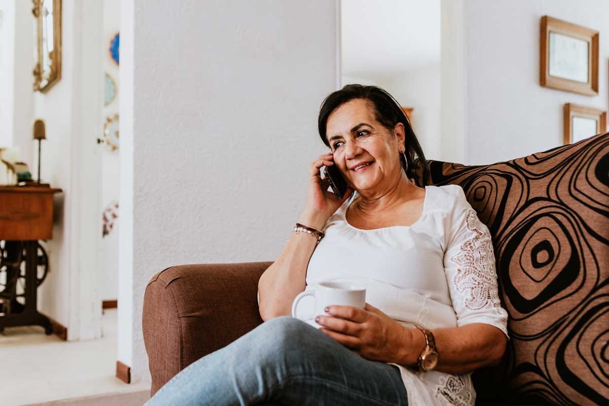 Elder woman sitting on the catch enjoying a phone conversation.