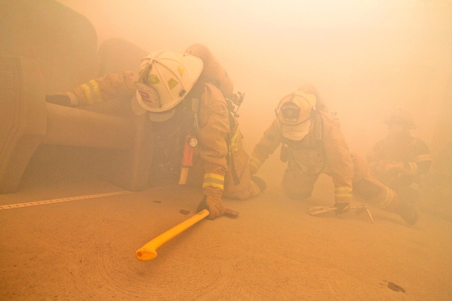 Air Force fire protection specialists perform a search in a smoke-filled  room during a simulated