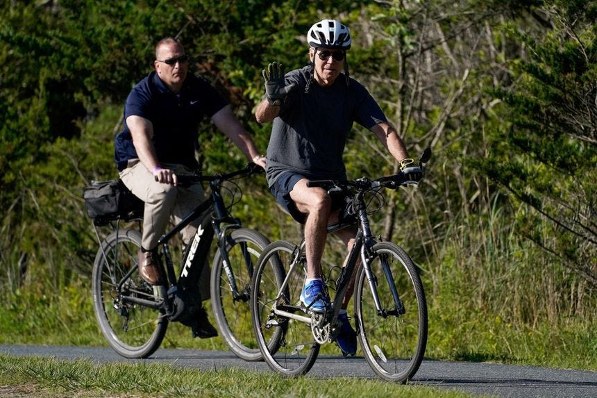 President Joe Biden waves while riding his bike in Rehoboth Beach, Delaware on June 18, 2022.