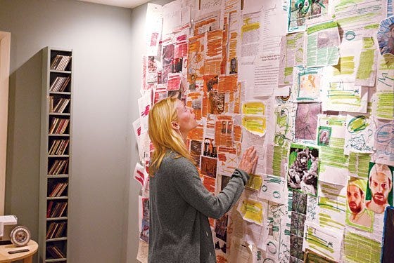 Carrie in her home, looking at her wall of ‘evidence’