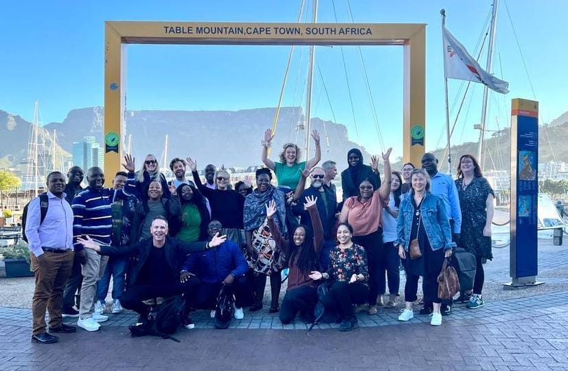 A group of people in a yellow tourist farme in from of table mountain