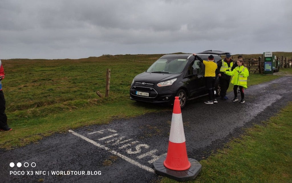 Finish is painted on the road, with volunteers sheltering by a car but still managing the finish line perfectly.