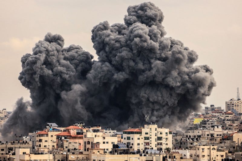 A giant, dark plume of smoke rises high over the homes and buildings of Gaza City during an Israeli airstrike.