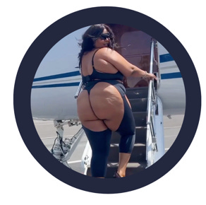 VERY large black woman (Lizzo) walking up stairs to a small jet