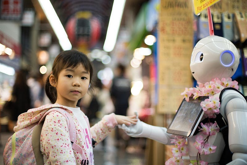 Small child shakes the hand of a robot.