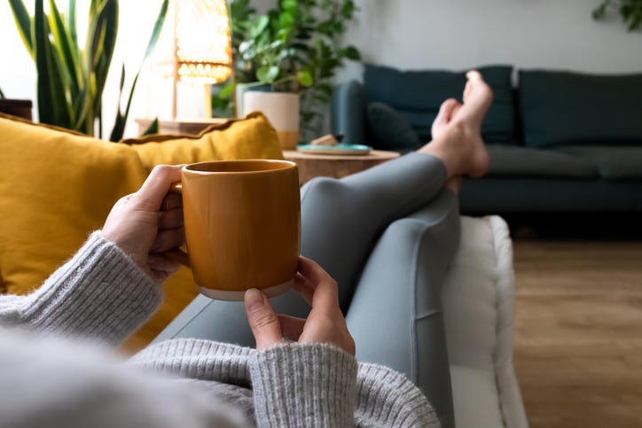 Woman relaxing with a warm drink and her feet up.