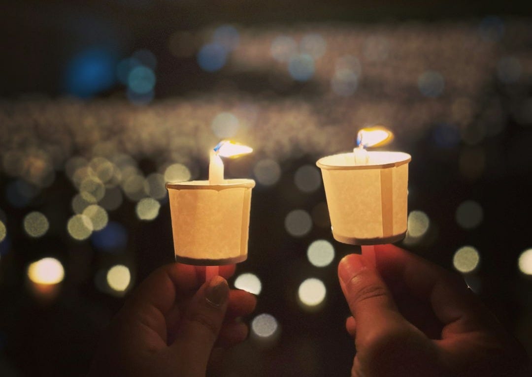 two people holding small candles in their hands two people holding small candles in their hands
