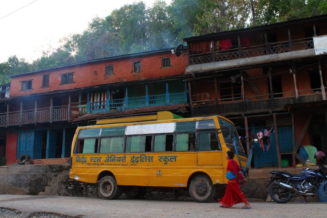 Yellow public bus parked outside of shops in Chandrawati.