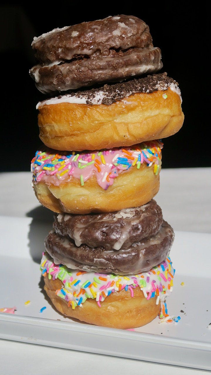 A stack of donuts with sprinkles

Description automatically generated