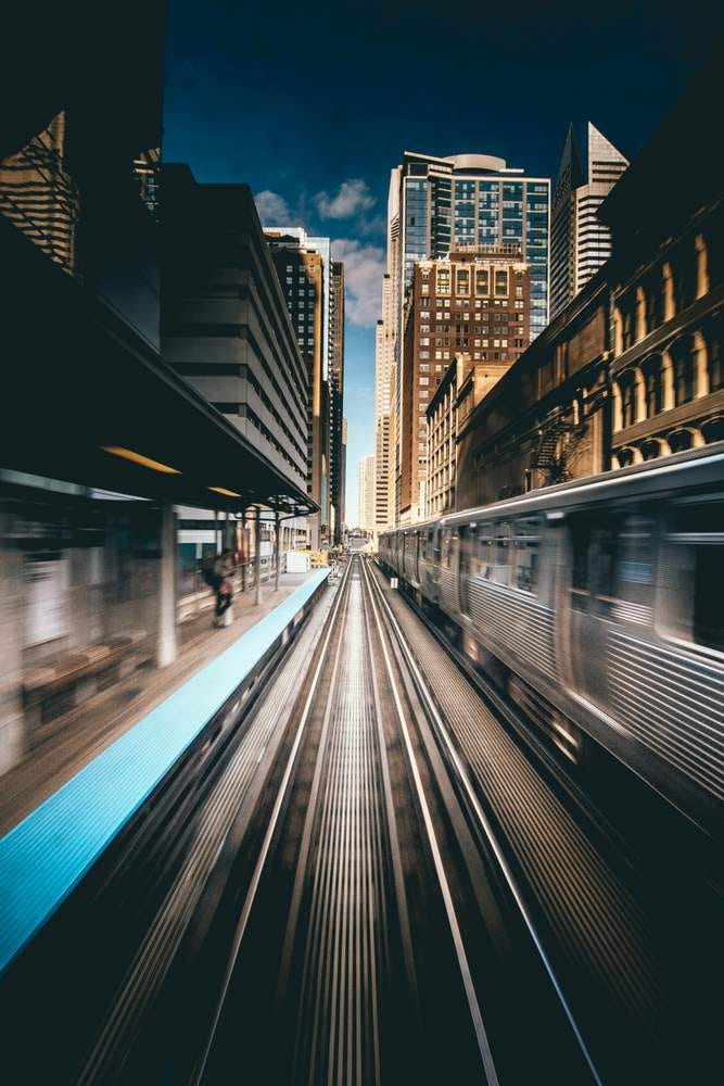 Photo of an urban train track with the blur of a train racing along it.