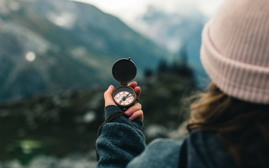 Woman with a compass looking at the mountain